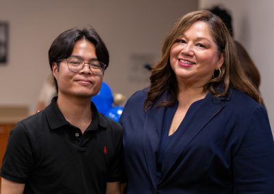 Two individuals pose together at an indoor event, smiling for the camera.