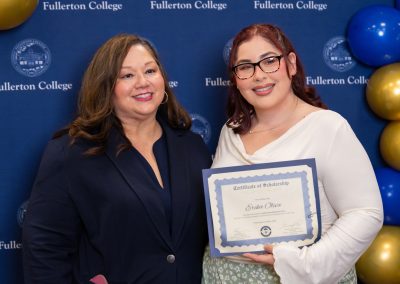 Two individuals pose together at a Fullerton College event, with one holding a scholarship certificate.