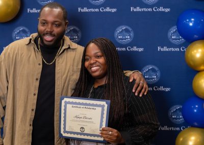 Two individuals pose together at a Fullerton College event, with one holding a scholarship certificate.
